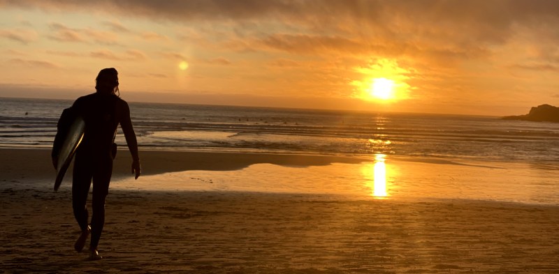Philipp Erich runs on the beach as he comes out of the water after a surf in Arrifana, Portugal, during a beautiful sunset.